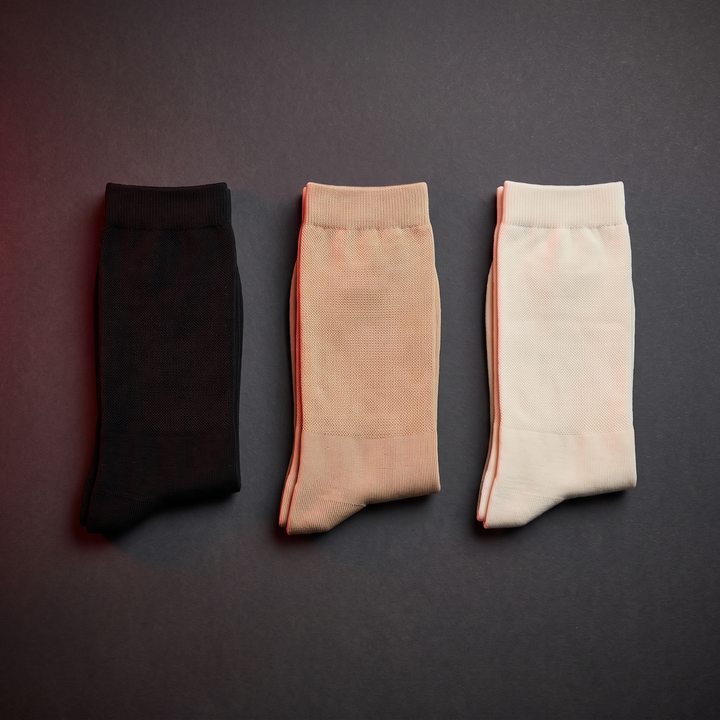 Flat lay of compression socks in black, beige, and ivory colorways