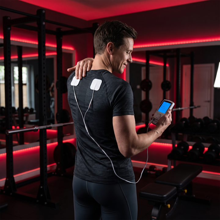 Applying EMS TENS muscle stimulator pad to shoulder for recovery