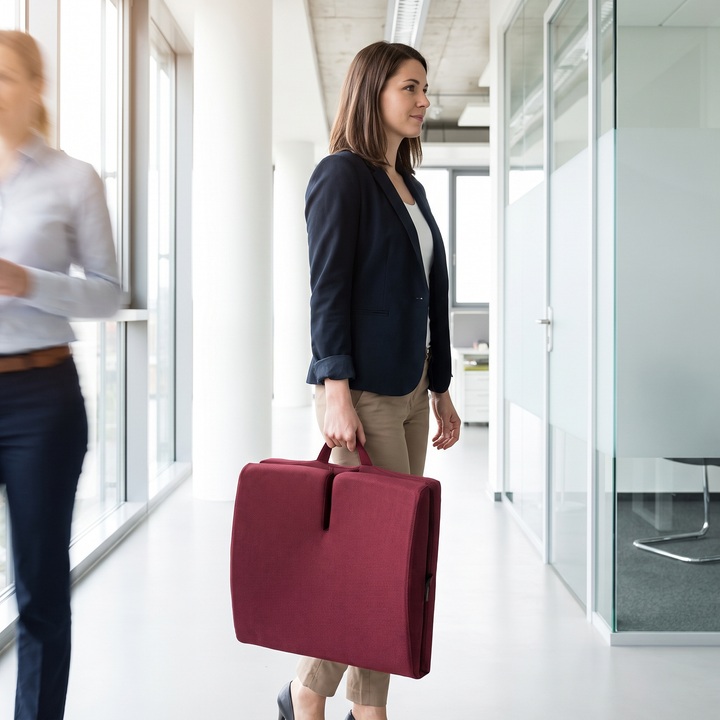 Portable ergonomic seat and lumbar backrest cushion being carried in an office setting