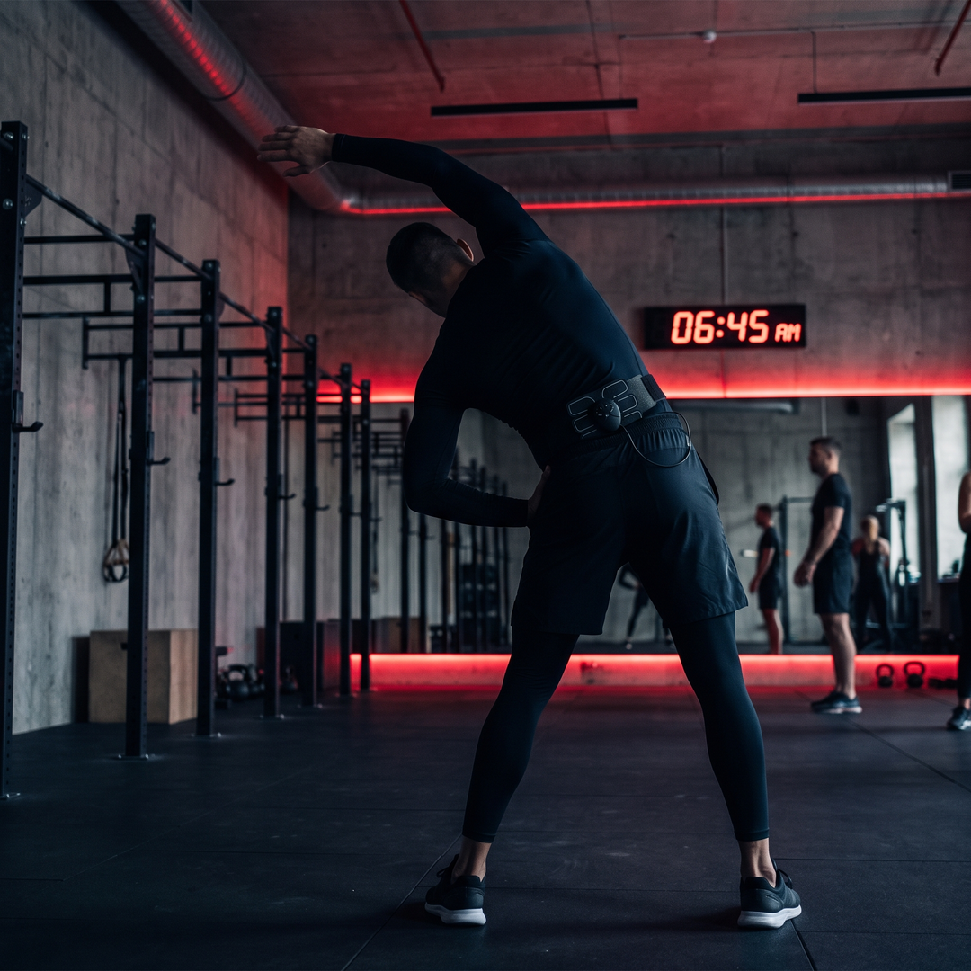 Athlete Using EMS Muscle Stimulation Device During Warm-Up Stretch