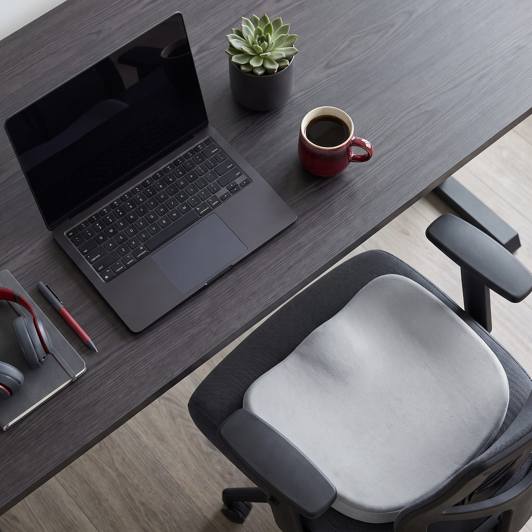Overhead view of a desk workspace with light grey seat cushion on an office chair