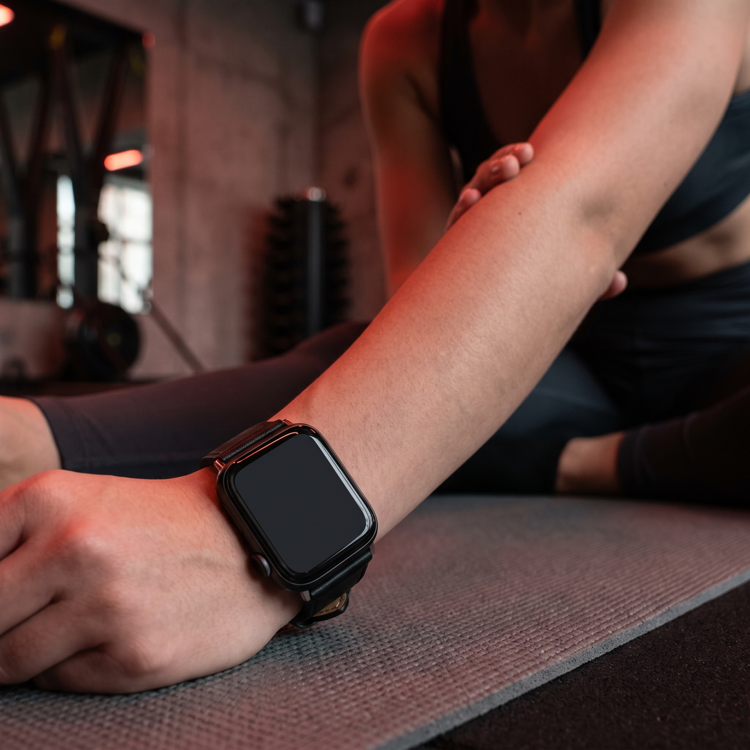 PHYSIOATHLETX smart fitness watch worn during a stretching recovery routine, black leather band
