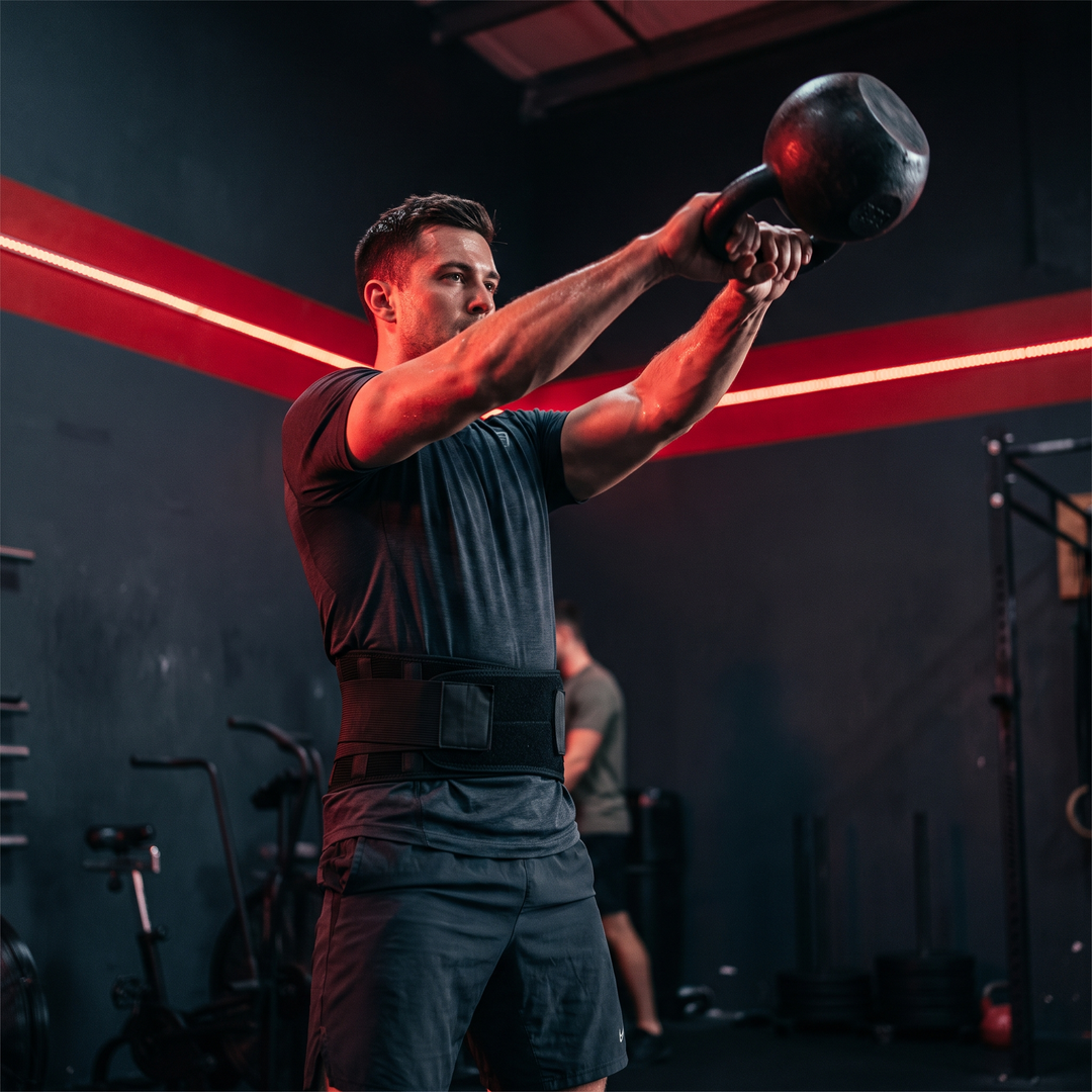 Athlete lifting kettlebell wearing PHYSIOATHLETX black waist support belt, gym-ready waist stability