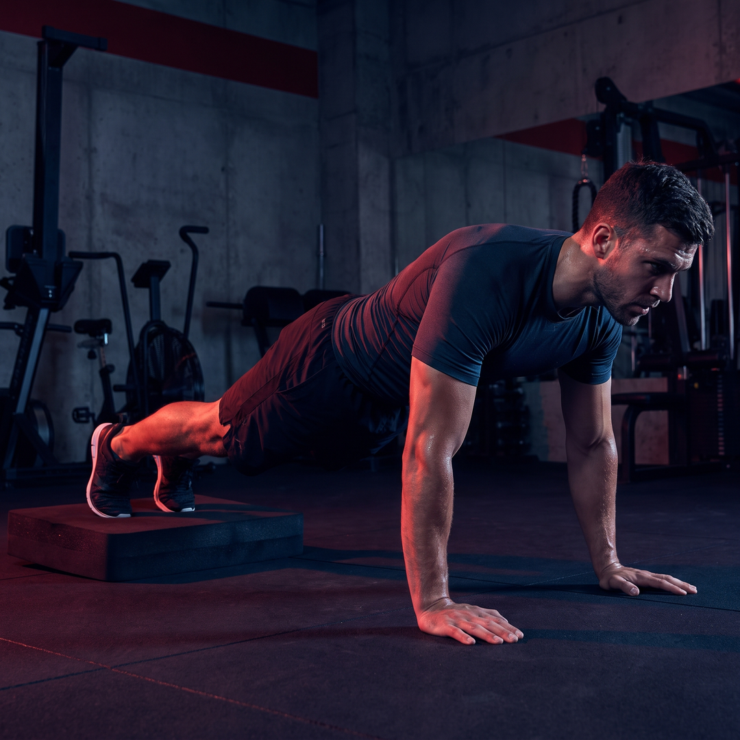 Athlete performing plank exercise with feet elevated on black PHYSIOATHLETX balance training pad for core strength