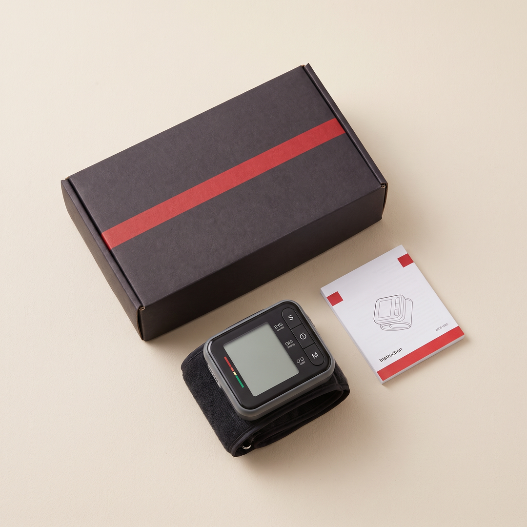 Home blood pressure monitor retail packaging flat lay with device and instruction booklet
