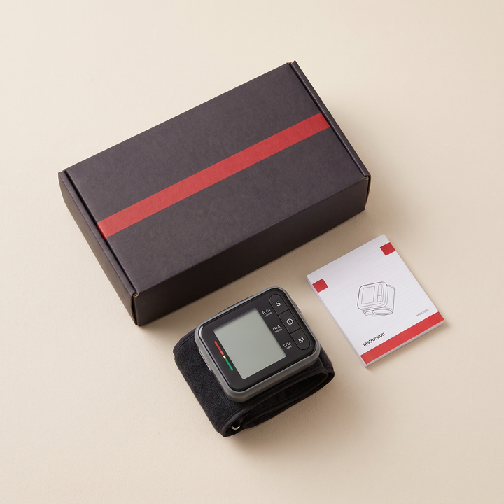 Home blood pressure monitor retail packaging flat lay with device and instruction booklet