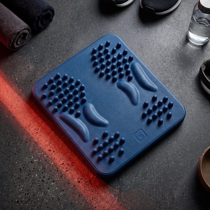 Top-down view of blue foot massage board on dark surface