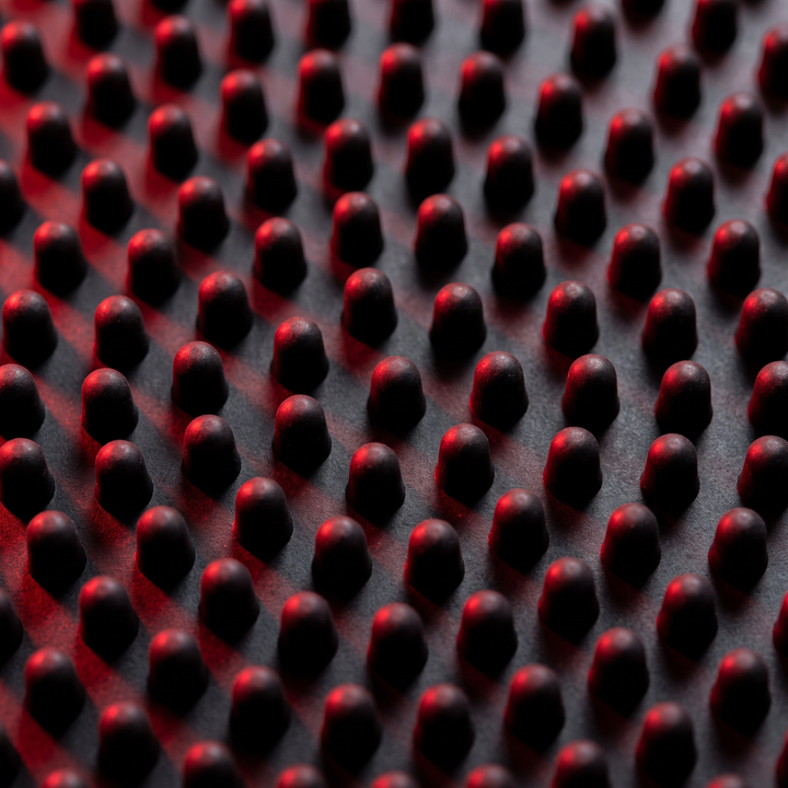 Detailed view of foot massage board peg pattern with dramatic lighting