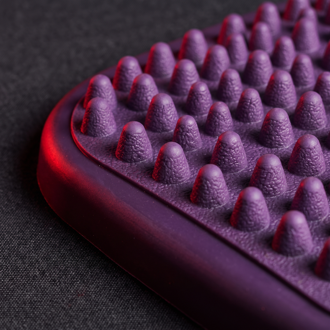 Close-up of textured peg surface on purple foot massage board