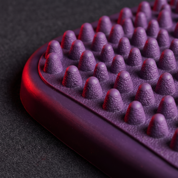 Close-up of textured peg surface on purple foot massage board