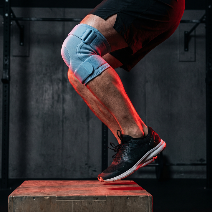 Athlete wearing light blue knee support strap during explosive jump training