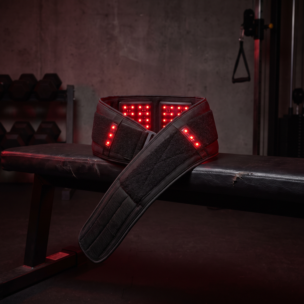 Black LED heat wrap recovery belt draped over a gym bench in a dark recovery studio