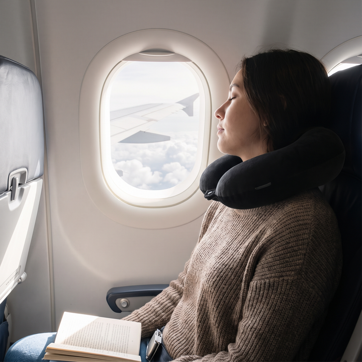 Traveler napping comfortably on an airplane using a U-shaped neck support pillow