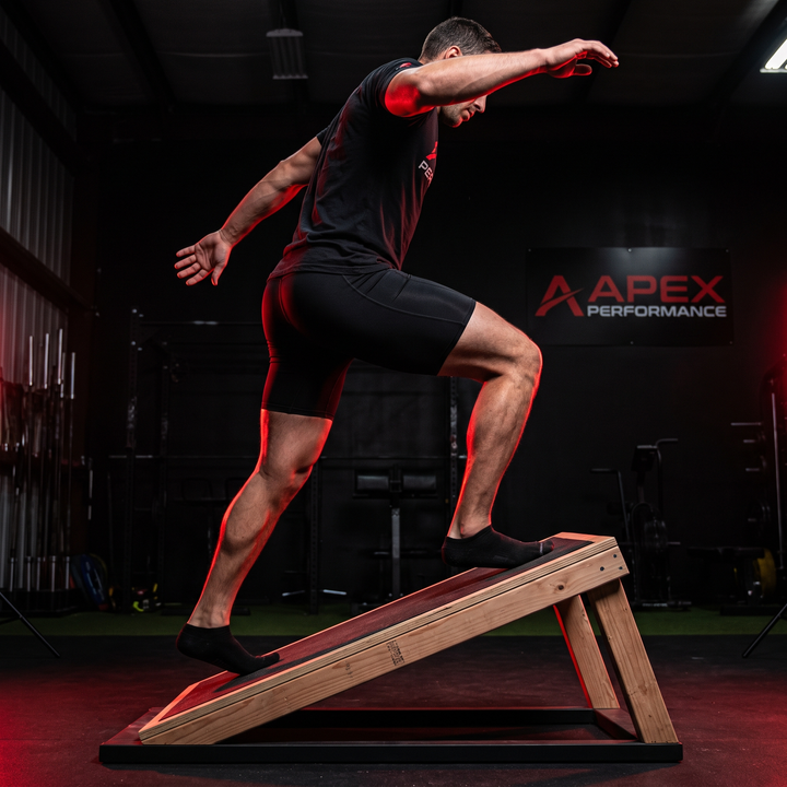Athlete performing an ankle mobility stretch on the PHYSIOATHLETX wooden incline board
